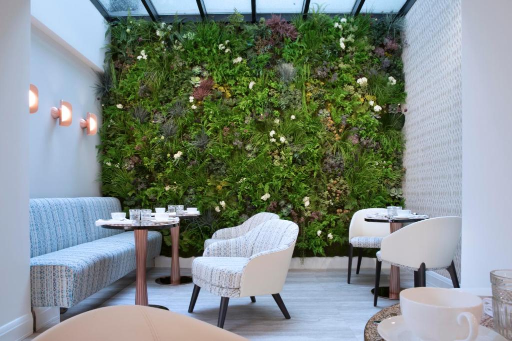 巴黎Hôtel Dress Code的餐厅内带桌椅的绿色墙壁