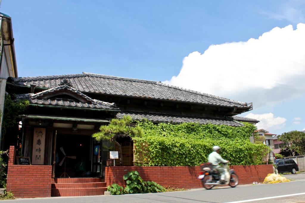 镰仓市Guest House Kamejikan -turtle time-的骑摩托车的人在建筑物前