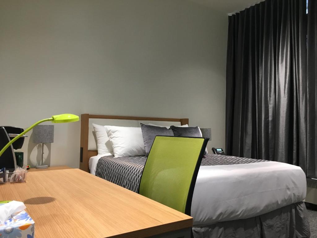 埃德蒙顿University of Alberta - PLH Accommodation的一间卧室配有一张床和一张带绿色椅子的桌子