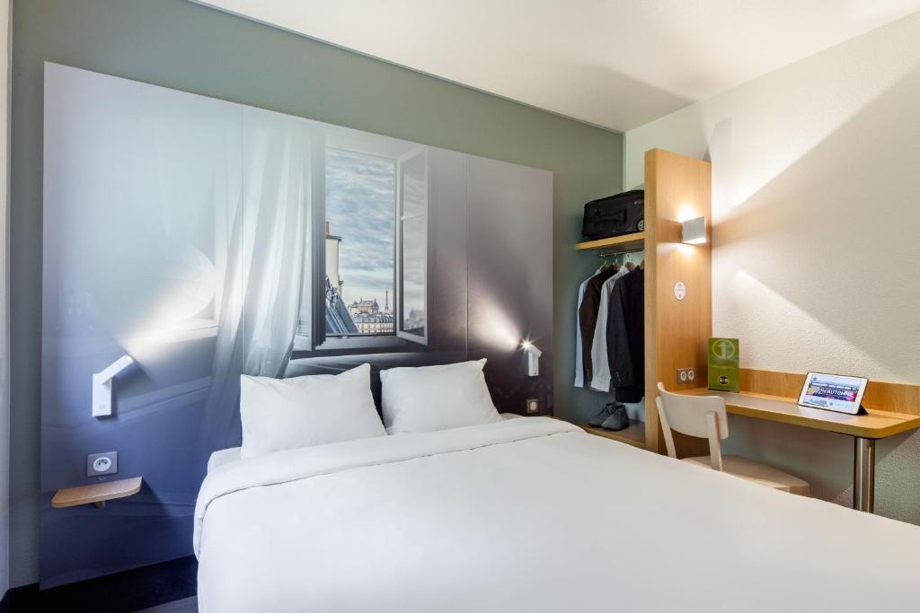 欧奈索斯博伊斯B&B HOTEL Paris Nord Aulnay-sous-Bois的一间卧室配有一张床、一张书桌和一个窗户。