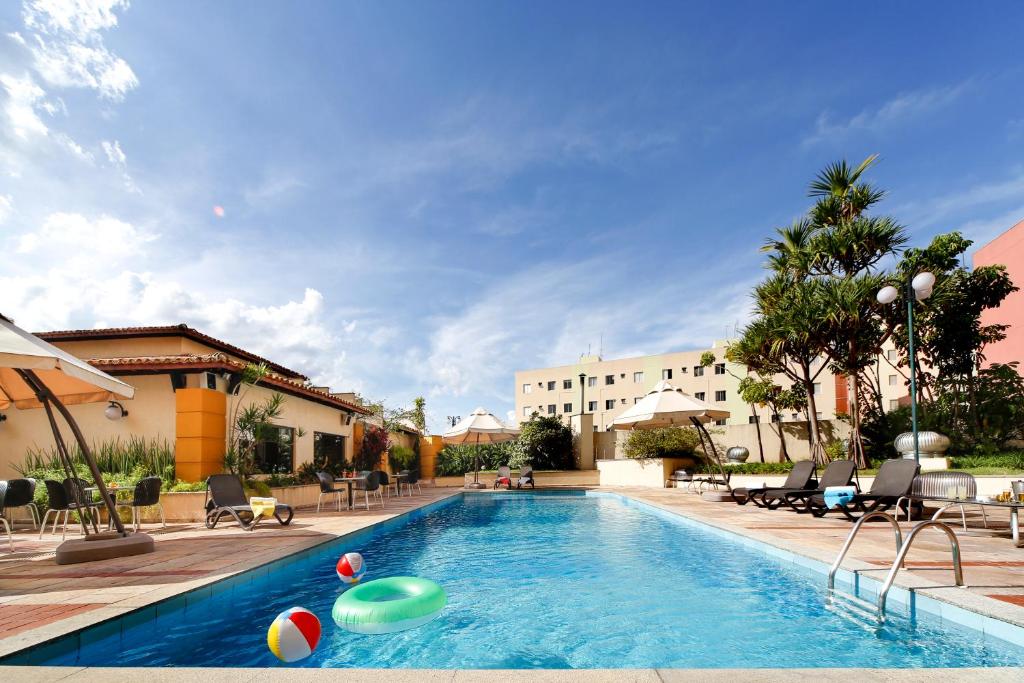 索罗卡巴Sorocaba Park Hotel by Atlantica的一座带排球和椅子的游泳池以及一座建筑