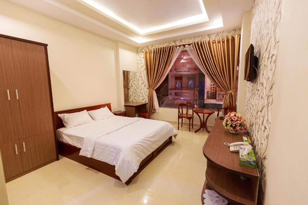 芹苴万乐酒店的一间卧室配有一张床、一张书桌和一个窗户。