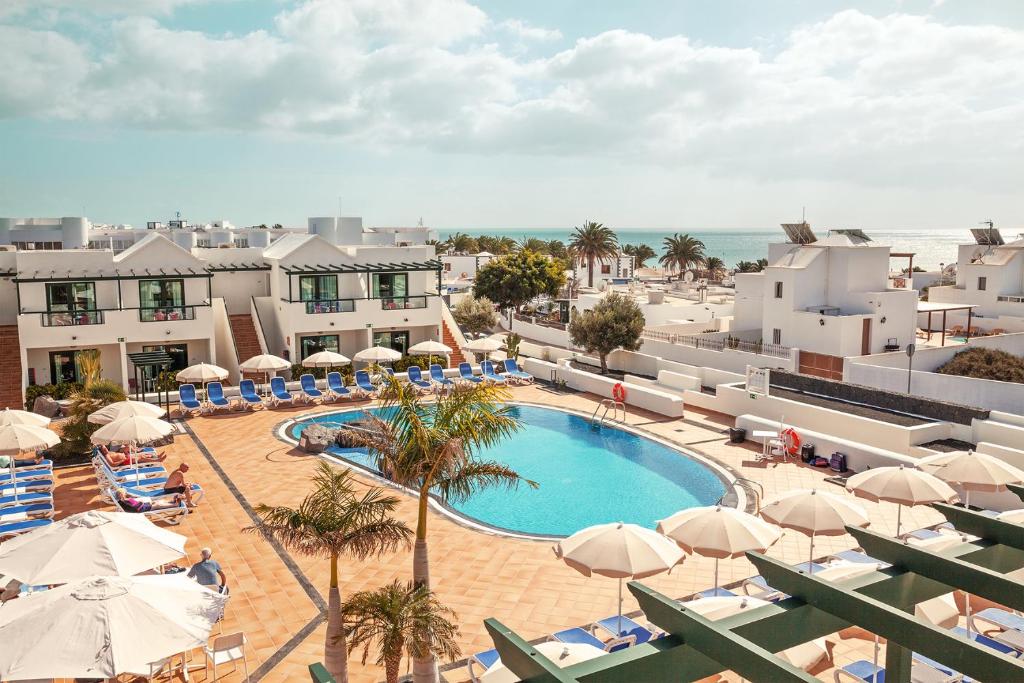 卡门港Hotel Pocillos Playa, solo Adultos的享有带遮阳伞的游泳池和大海的景致。