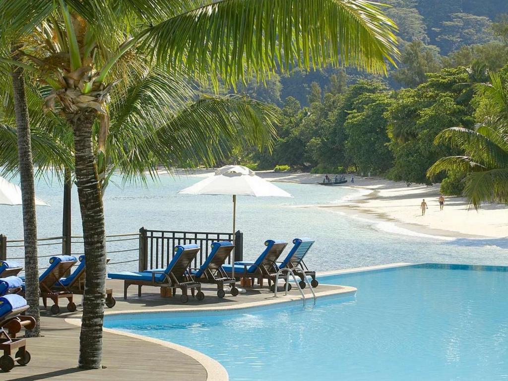 贝尔欧布莱Fisherman's Cove Resort的海滩旁的游泳池配有椅子和遮阳伞