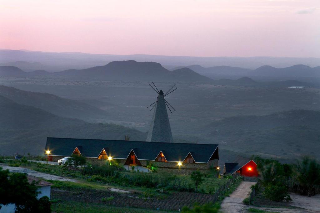 Serra de São BentoPousada Pedra Grande的山顶上一座风车,有一座建筑