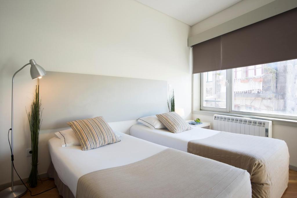 波尔图三一公寓酒店的带窗户的客房内的两张床