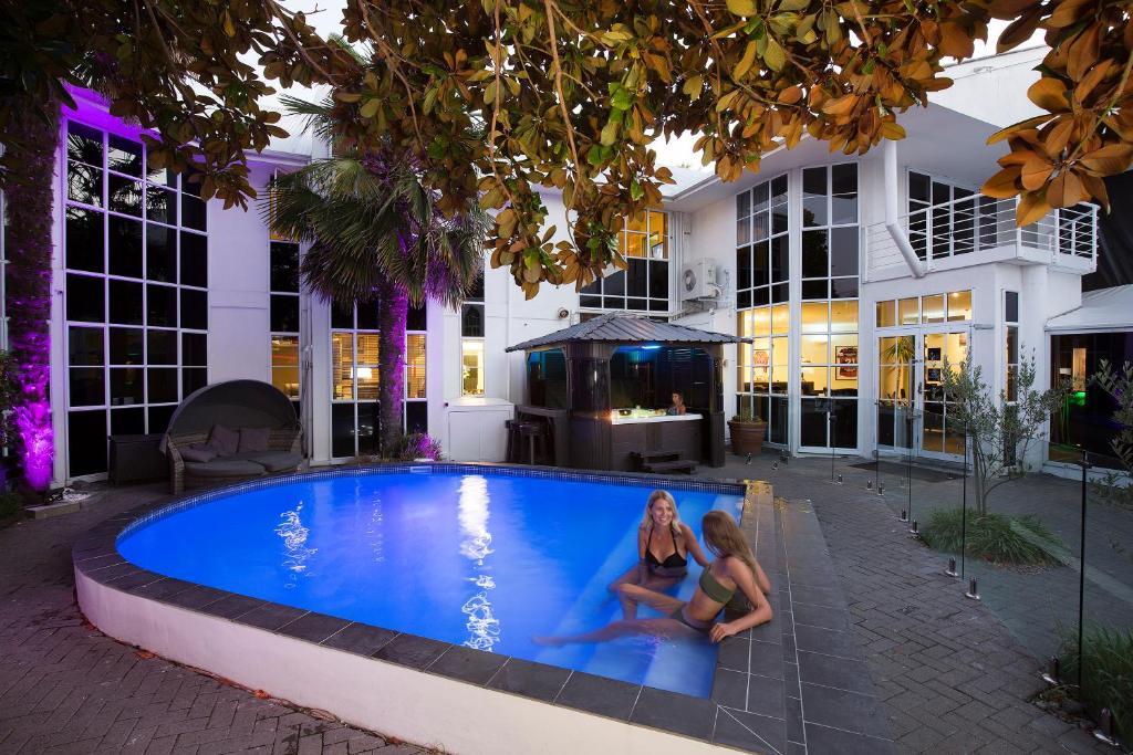 基督城帕威林酒店的两个女人坐在一座建筑物前的游泳池里