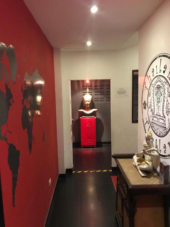 南芭堤雅Lotus Art Guesthouse的走廊上,有雕像,有红色墙壁的房间