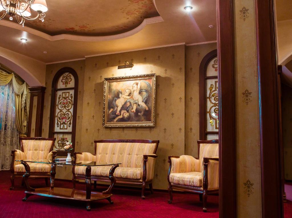 乌日霍罗德Hotel Elefant的一间设有椅子的房间和墙上的绘画