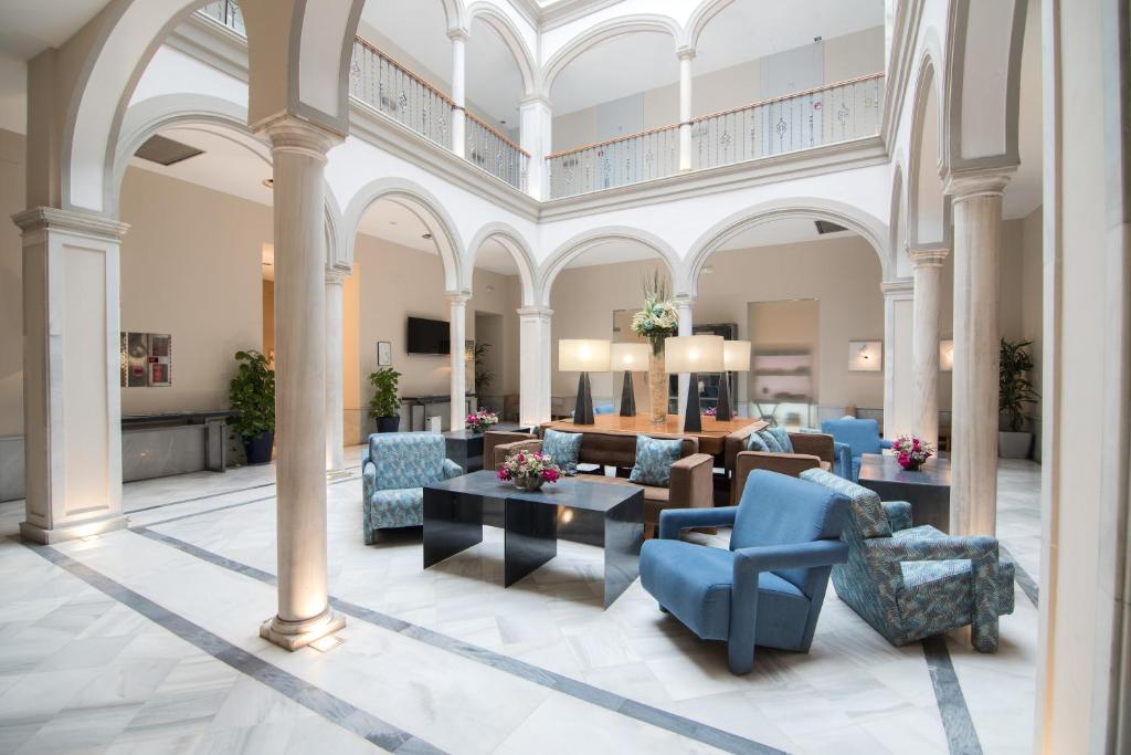塞维利亚珀蒂宫马克斯圣安娜高科技酒店的大型客厅配有蓝色的椅子和桌子