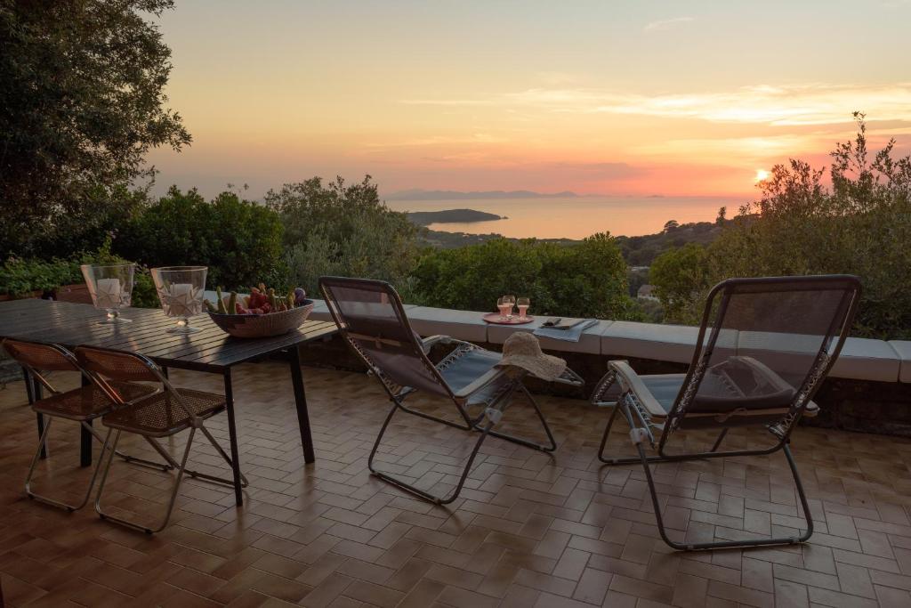 蓬塔阿拉Punta Ala Luxury Villa的露台上的桌椅享有日落美景