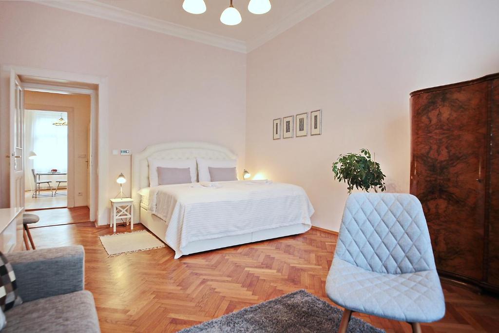 布拉格布拉格中心公寓的一间白色卧室,配有一张床和两把椅子