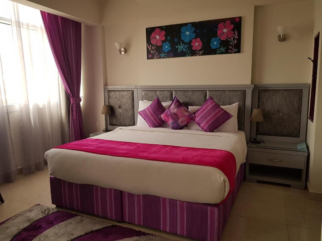 科威特科威特欧陆酒店的一间卧室配有一张大床,提供粉色和紫色枕头