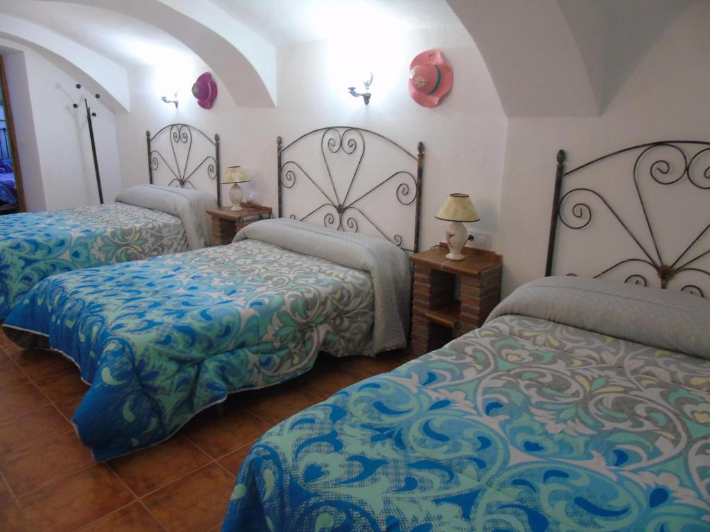 瓜迪克斯Cueva El Jaraiz的一间卧室配有两张带蓝色和绿色床单的床