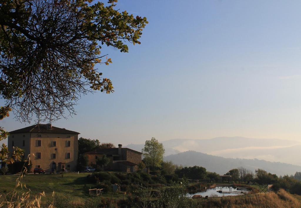 MontecastelliFattoria San Paolo Agriturismo的山丘上的房子,后面有湖泊和山脉