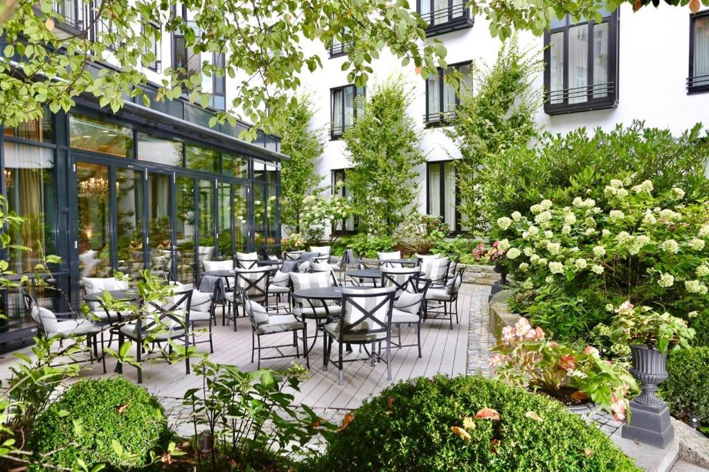 慕尼黑慕尼黑皇宫酒店的户外庭院设有桌椅和鲜花