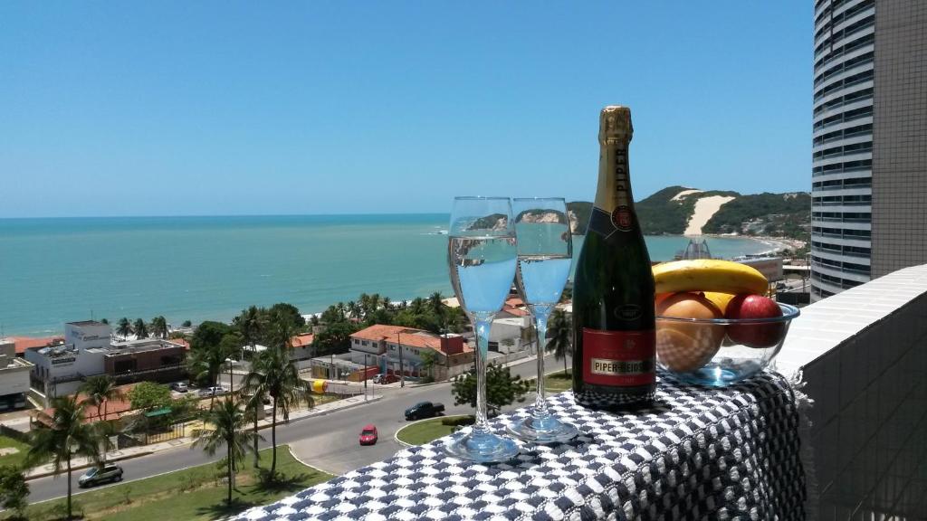 纳塔尔Natal Prime - Porto Imperial的阳台上的桌子上放有一瓶葡萄酒和玻璃杯