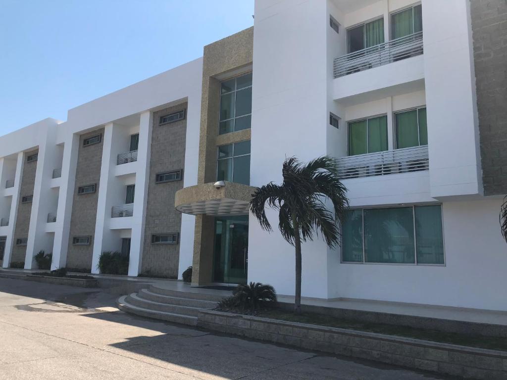 巴兰基亚Hotel Via 40的一座白色的建筑,前面有棕榈树