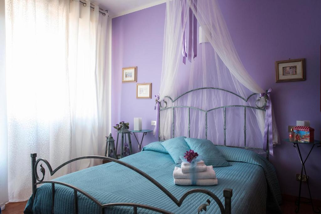 阿巴迪亚圣萨尔瓦托雷Albergo La Bussola的紫色卧室配有带毛巾的床