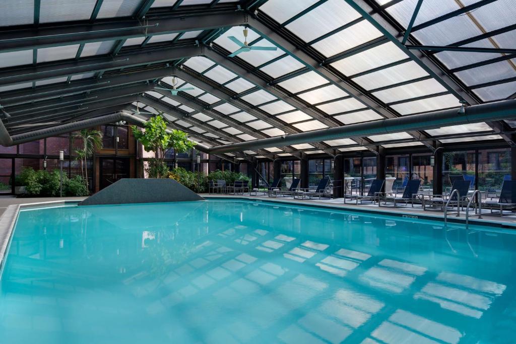 普林斯顿普林斯顿凯悦酒店 的一个带玻璃天花板和椅子的室内游泳池