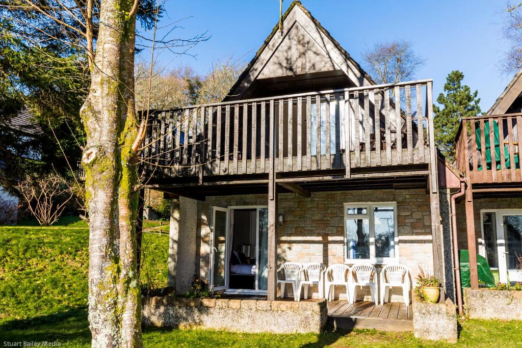 甘尼斯莱克Cornwall Countryside Lodges "Reserve Worldwide" Honicombe的门廊上带甲板和椅子的房子