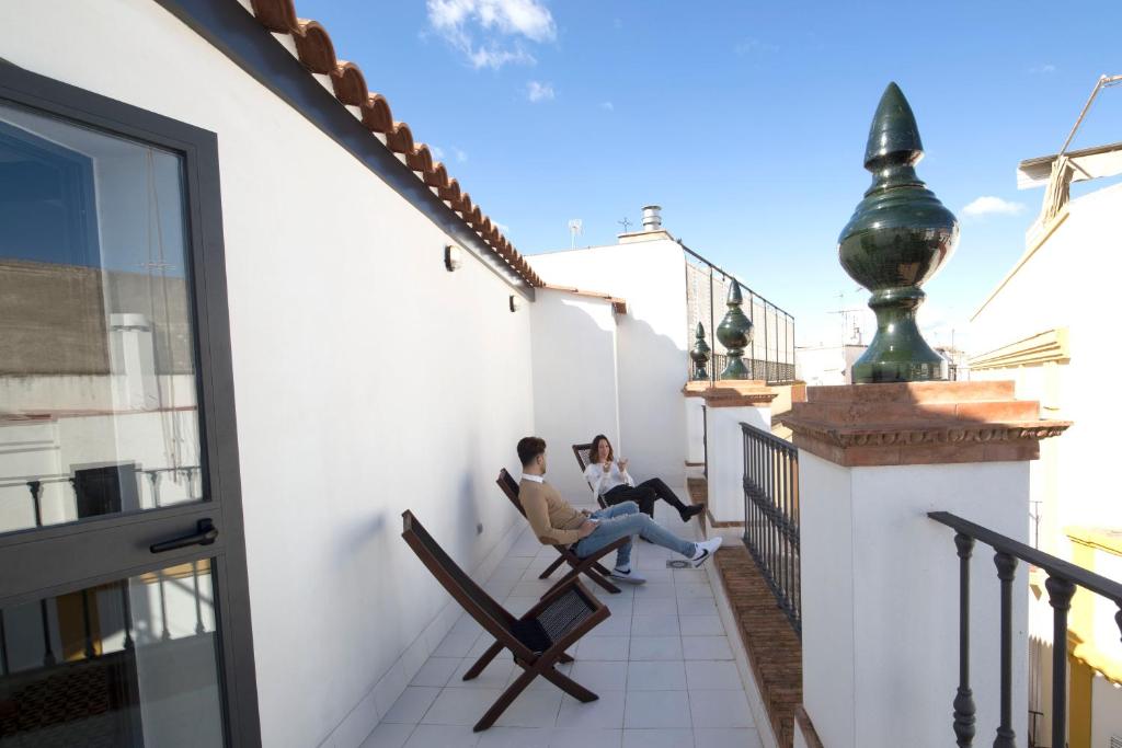 塞维利亚U-Sense For You Hostel Sevilla的两人坐在房子的阳台上