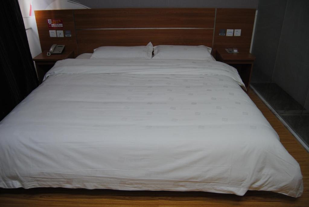 Nancun尚客优连锁河北石家庄高新区祁连街店的一张带白色床单和枕头的床