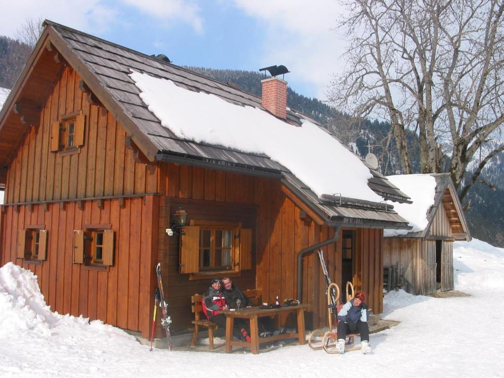 陶普利茨Egghartguthütte的两个人坐在小屋外的雪地里