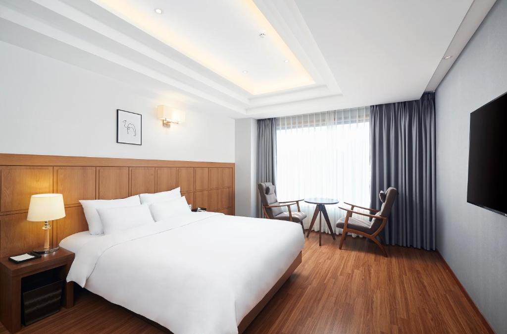 釜山雄狮酒店的酒店客房设有一张白色大床和一张桌子。