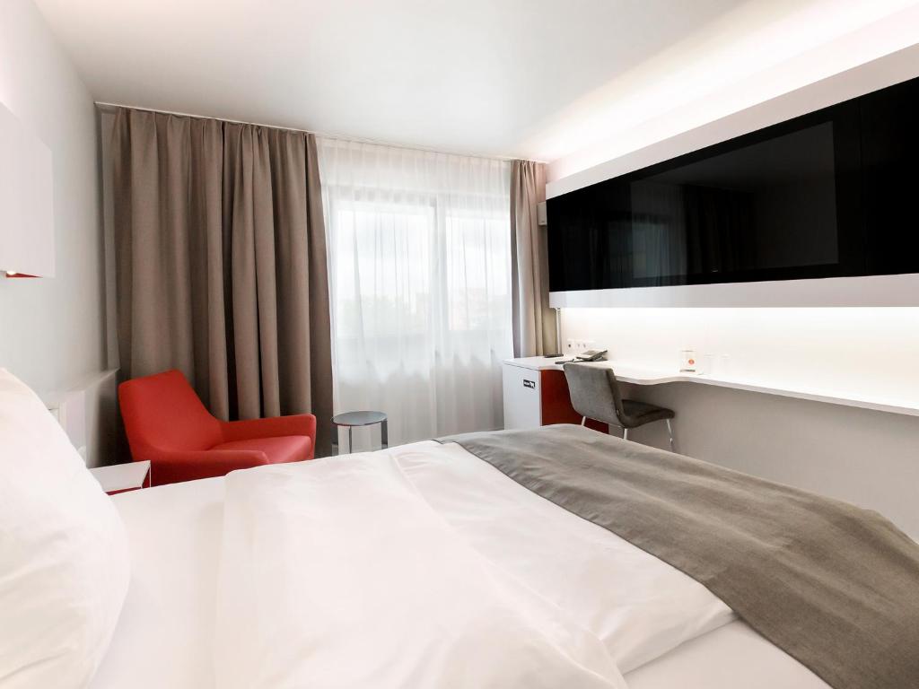 汉诺威汉诺威多梅洛酒店的酒店客房设有一张大床和一张红色椅子。