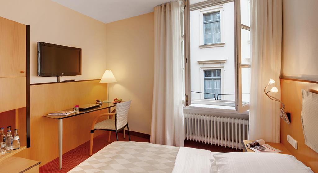 奥格斯堡市政厅酒店的配有一张床、一张书桌和一扇窗户的酒店客房