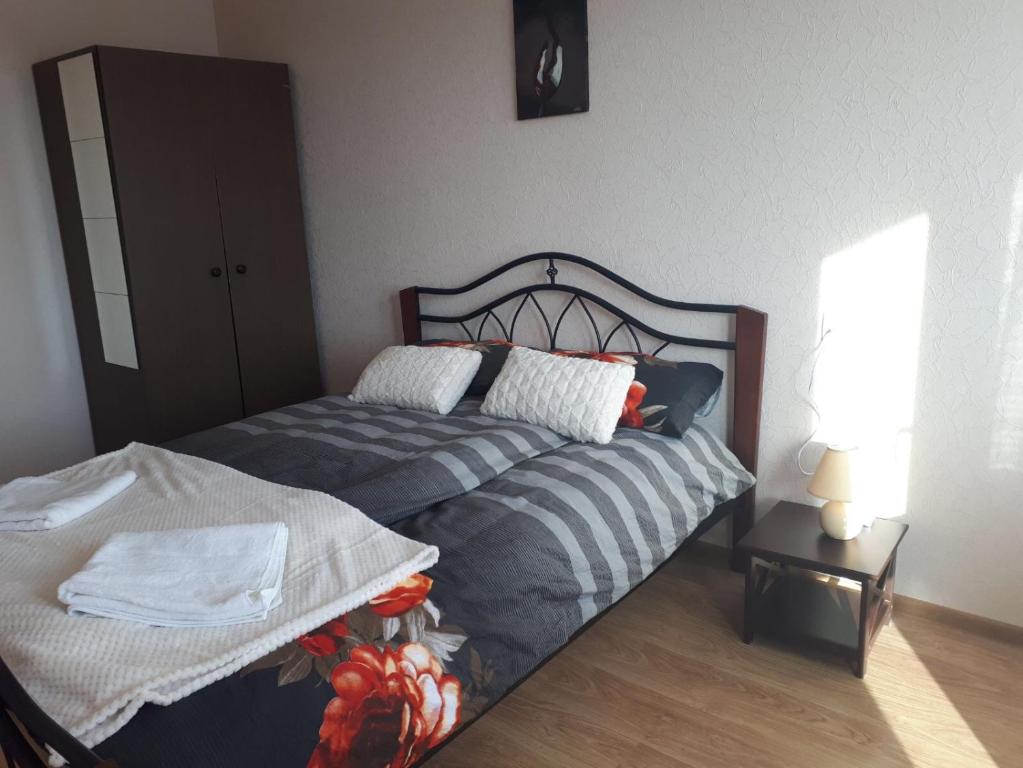 ĒrgļiErgli Apartment的一间卧室配有一张床和一张带台灯的桌子