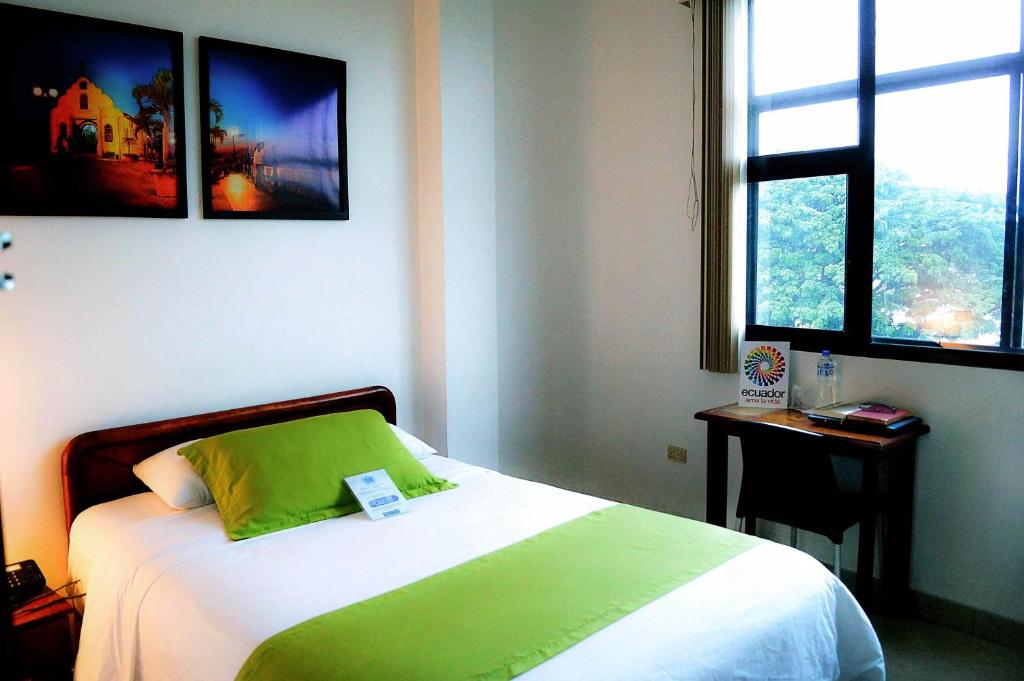 瓜亚基尔卡斯特利酒店的一间卧室配有一张带绿色枕头的床