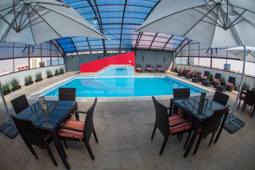 墨西哥城里亚索机场酒店的一个带桌子和遮阳伞的室内游泳池