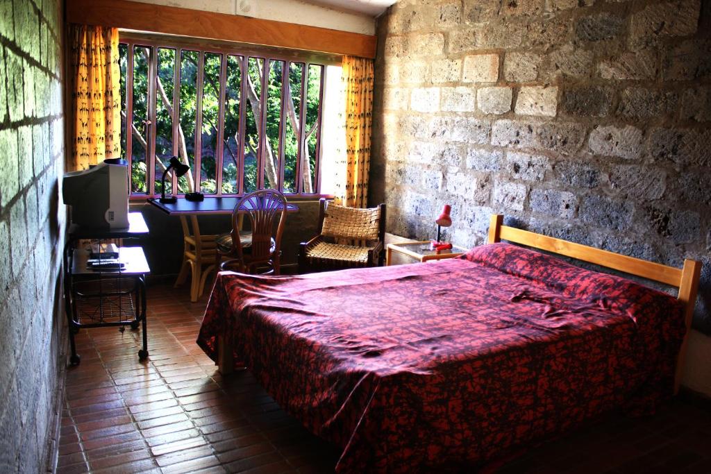 内罗毕Villa Rock Stop Falls的一间卧室配有一张床、一张书桌和一个窗户。