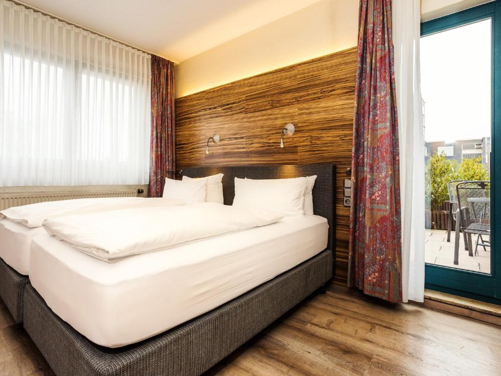 贝尔吉施格拉德巴赫Hotel & Wirtshaus Hansen的一间卧室设有一张大床和一个大窗户