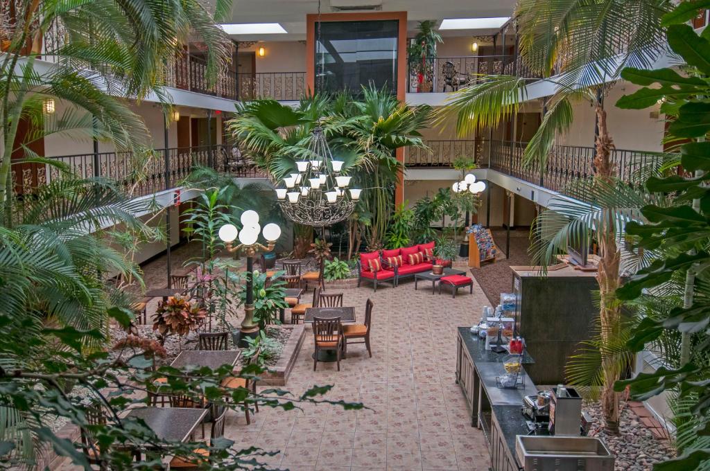 俄克拉何马城Governors Suites Hotel Oklahoma City Airport Area的大堂设有桌椅,种植了棕榈树。