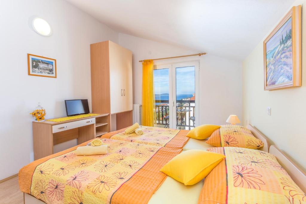 赫瓦尔Apartments and Rooms Ivanović的卧室设有两张床、书桌和电视。