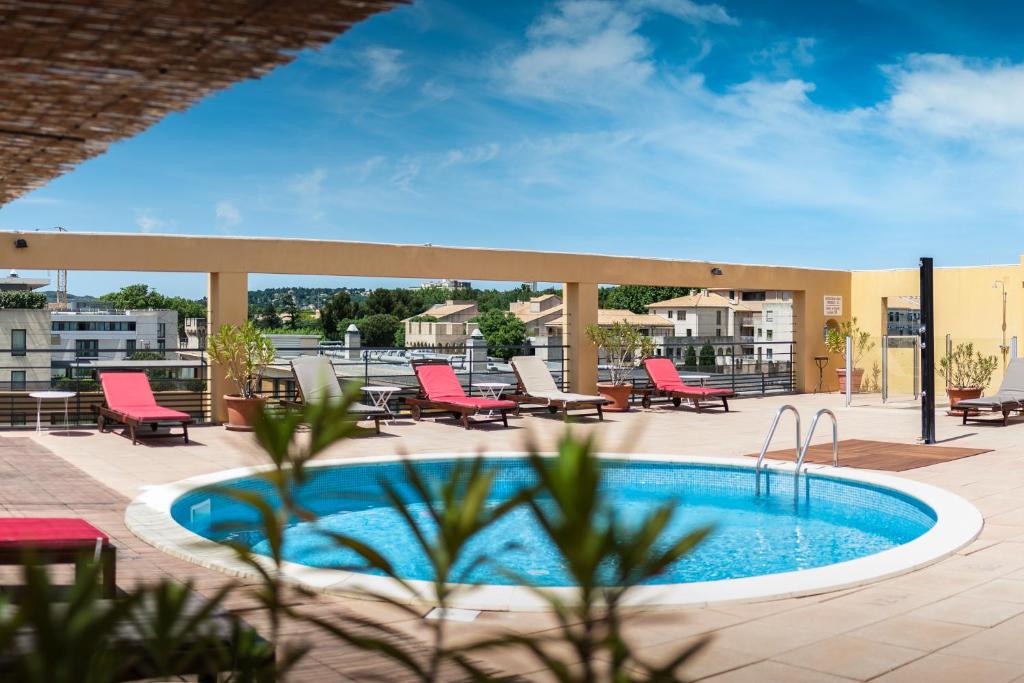 阿维尼翁阿维农豪华酒店的一个带红色椅子的游泳池和一个庭院