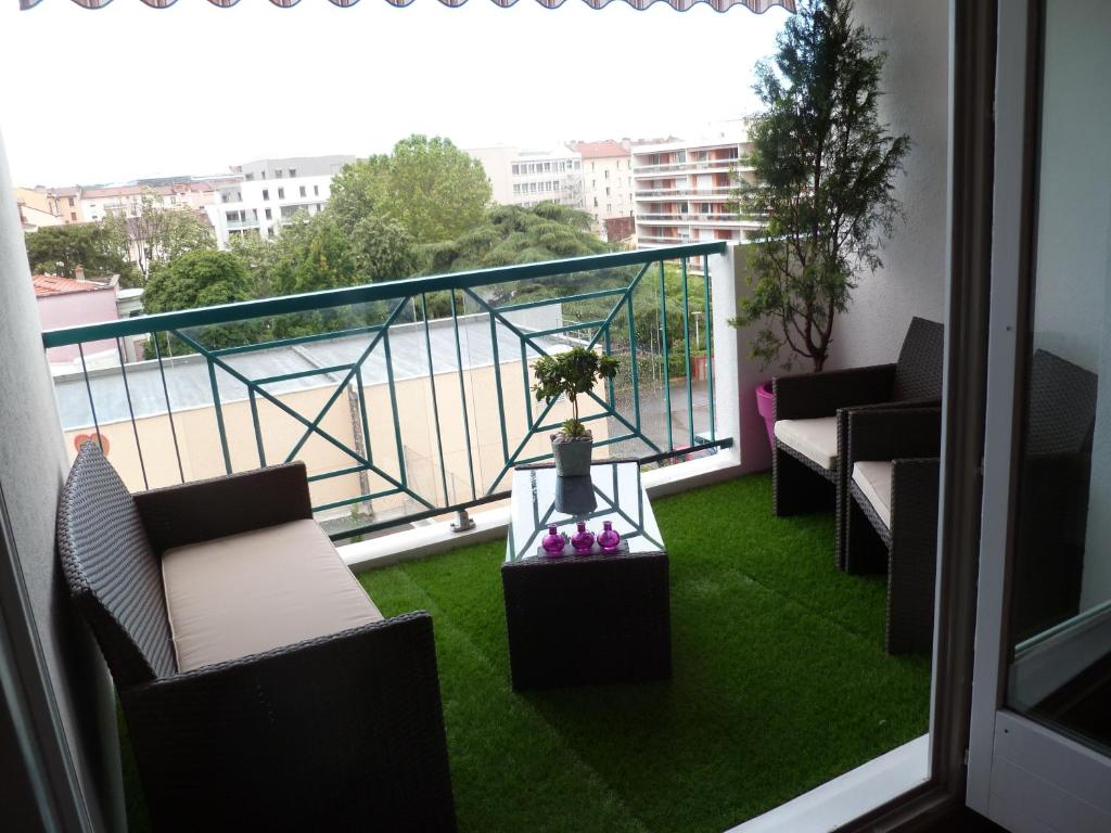 里昂乐贝里尼酒店的阳台配有椅子和桌子,位于草地上