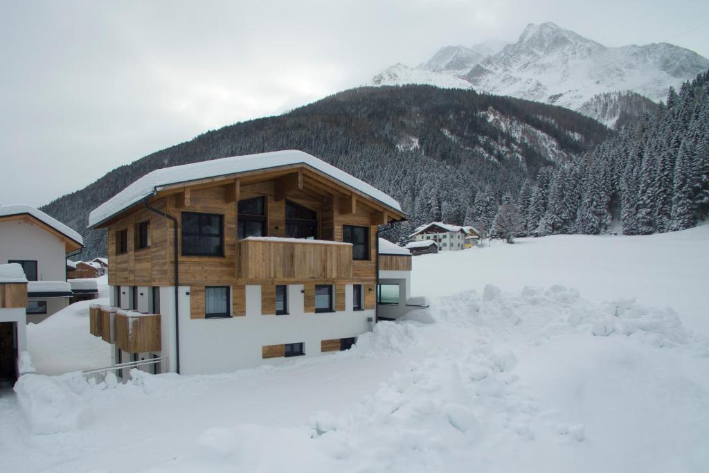 佩特诺伊阿尔贝格贝拉小木屋的一座被雪覆盖的建筑,背景是群山