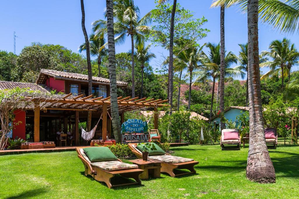 普拉亚埃斯佩洛Pousada Enseada do Espelho的一个带吊床和椅子的度假村,并种植了棕榈树