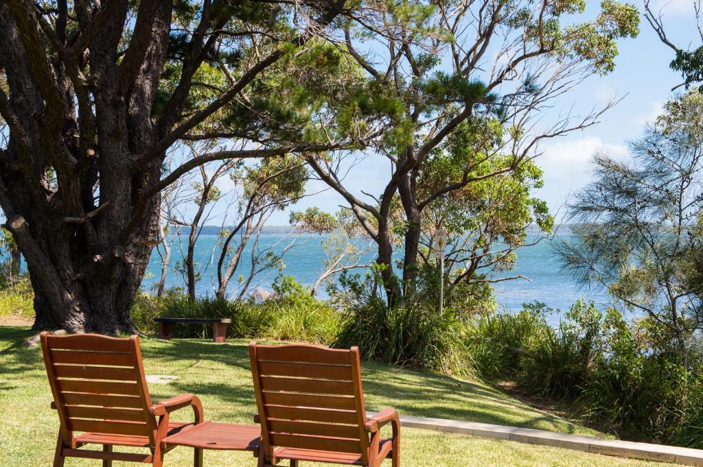 圣殿海岬海滩住宿加旅馆自助式公寓的两把椅子坐在水边的草地上