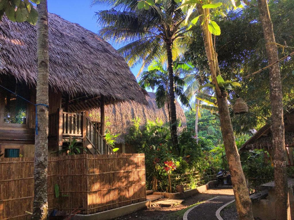 巴图卡拉爪哇梦耶别墅的茅草屋顶和棕榈树度假屋