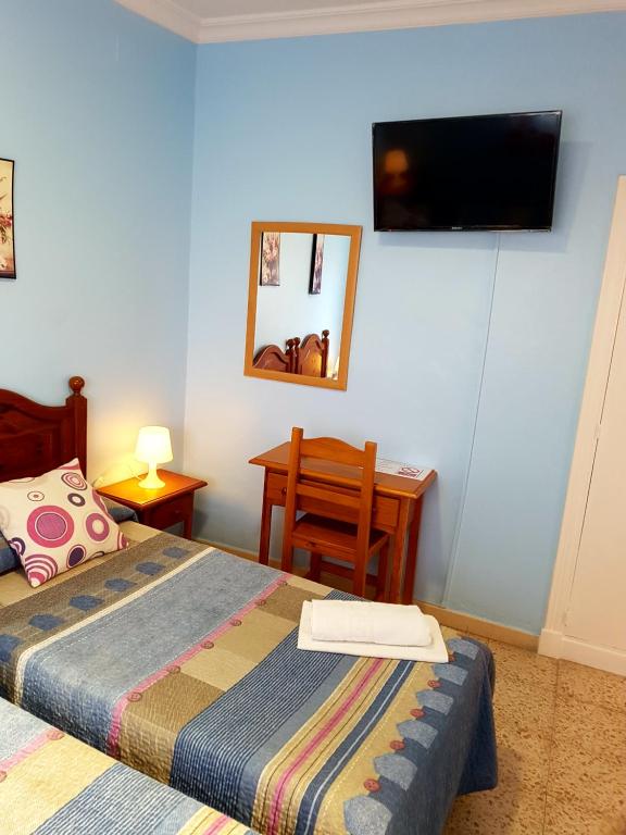 赫雷斯-德拉弗龙特拉Sanvi Xerez Centro的卧室配有一张床,墙上配有电视