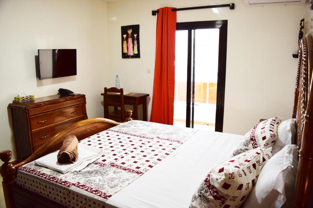 达喀尔Kakatar Family Residence , Yoff的一间卧室配有一张床、梳妆台和电视。