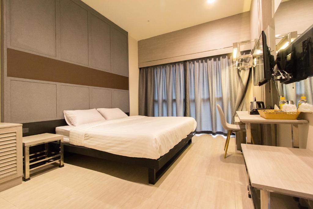 曼谷懒人星期天旅社的酒店客房配有一张床、一张书桌和一台电视。