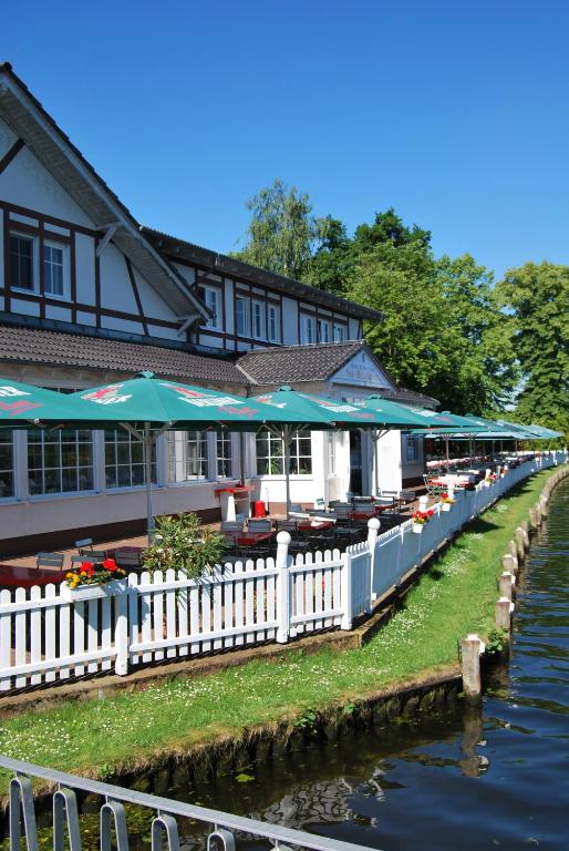 柏林Neu-Helgoland的河边的一座带桌子和遮阳伞的建筑