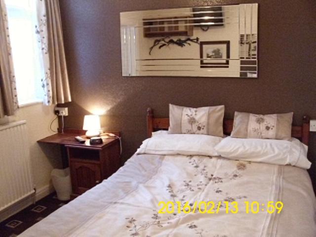 布莱克浦Seaforth Guest House - Pleasure Beach的一间卧室配有一张床和一张带台灯的桌子