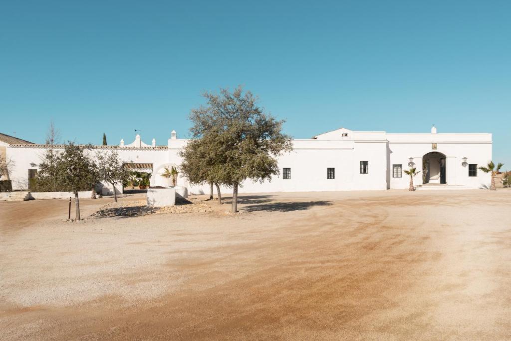 赫雷斯-德拉弗龙特拉HACIENDA LAS MESAS - Luxury Villa Jerez的前面有一块泥地的白色建筑